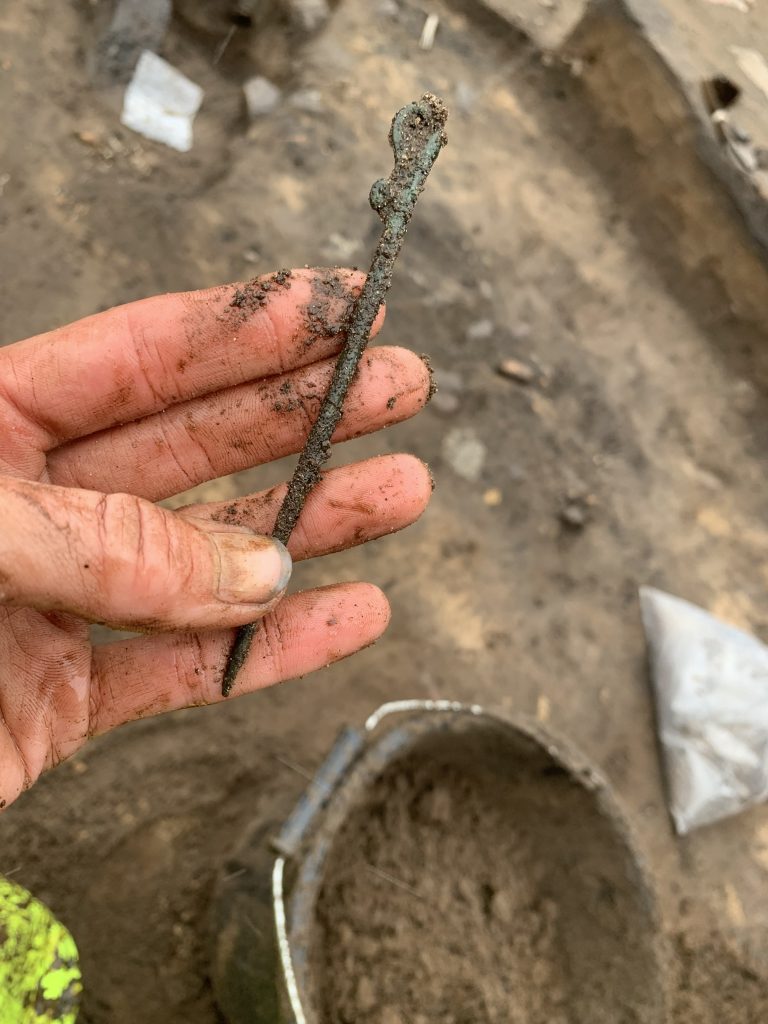 Bronze pin covered in mud, recently discovered from the ground