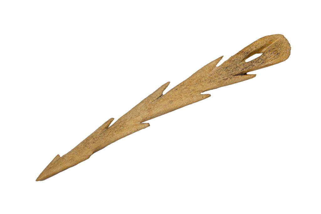 prehistoric harpoon on a white background. Made from bone, long and think with sharp edges